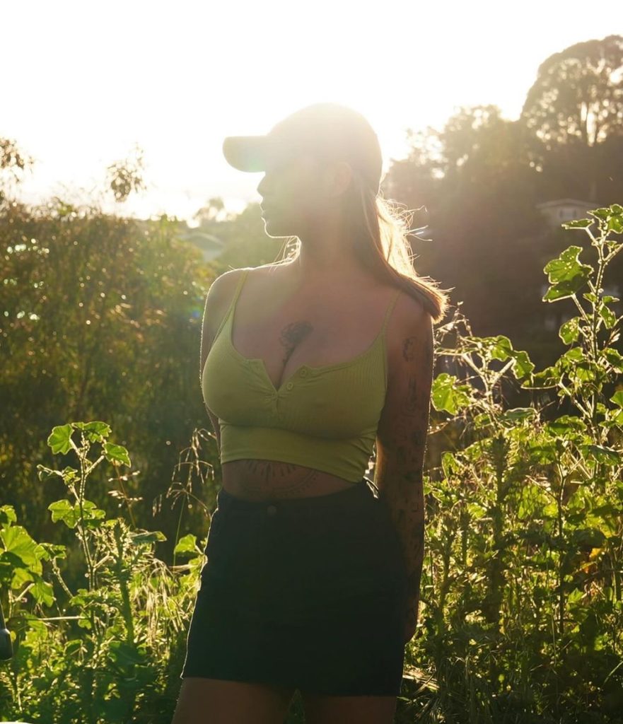 Sexy Asian girl with big boobs wearing a tight top among greenery