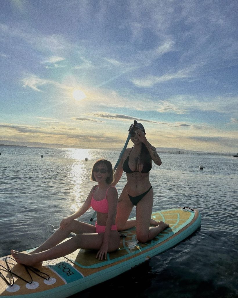 A couple of Asian girls enjoying themselves on a surf board in the ocean