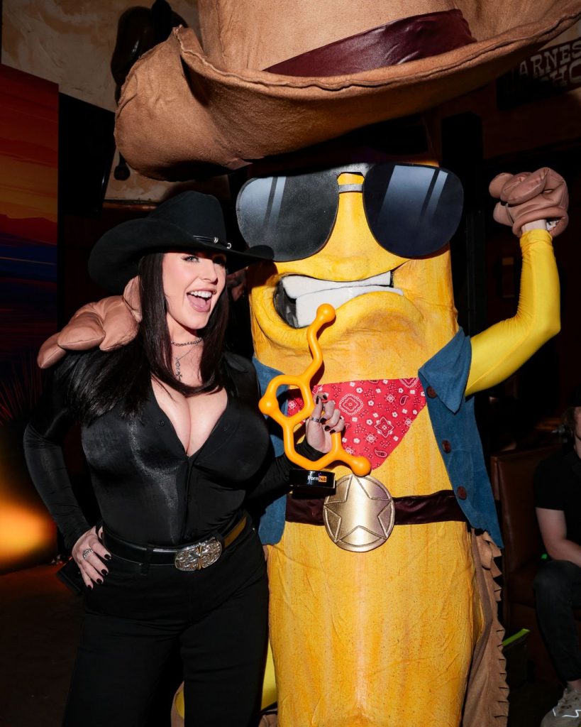Big tit cowgirl posing next to a giant corn figure wearing a cowboy outfit
