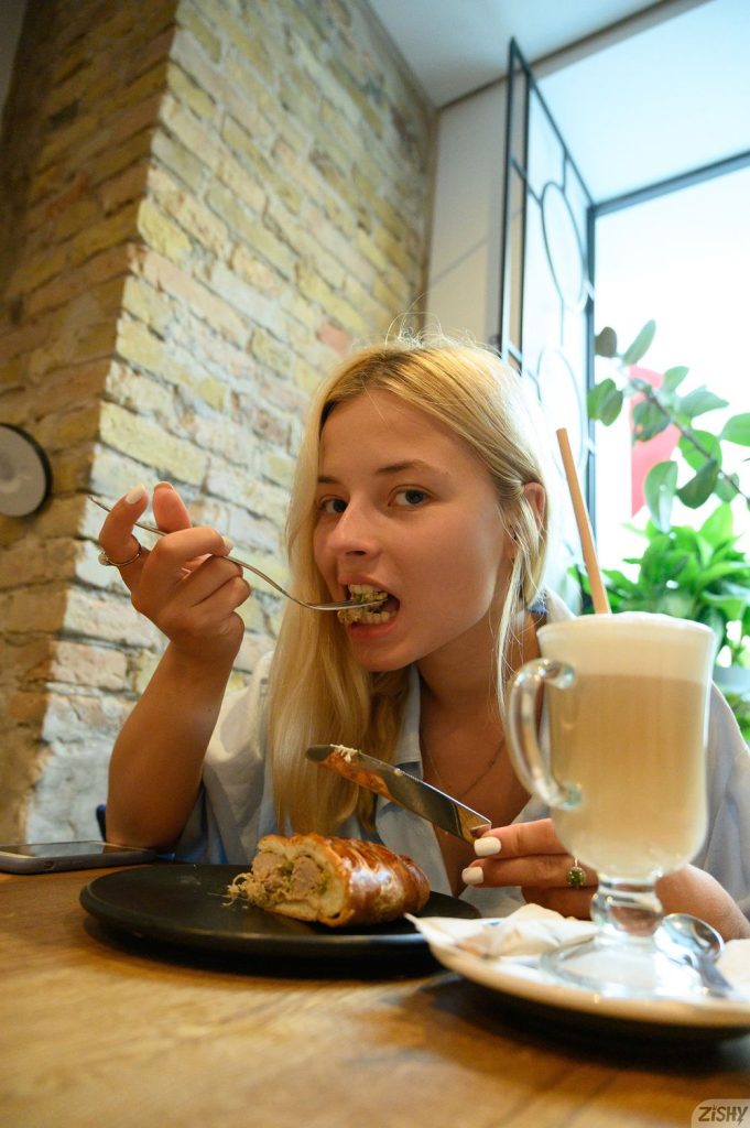 Pretty blonde with a fork full of food at the table of a restaurant