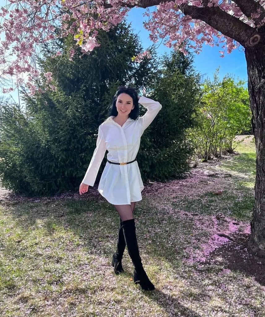 Pretty brunette posing outdoors among spring flowers