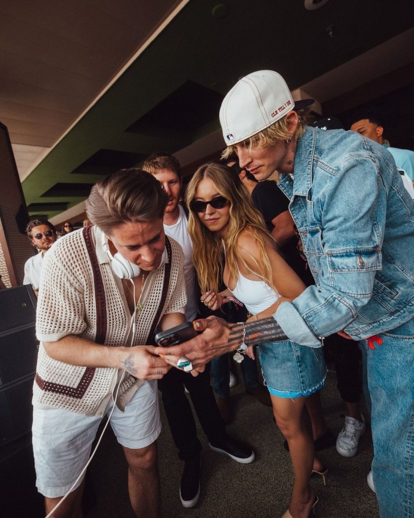 Sexy blonde celebrity looking at a phone together with two male celebs