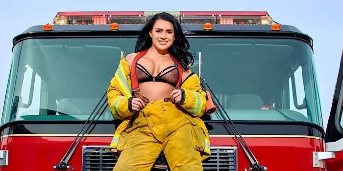 Sexy fire fighter pulls her jacket open to reveal tits in a bra