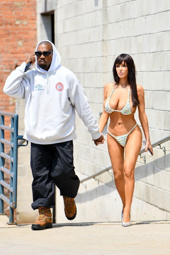 Bianca Censori big boobs and showing off her body in a candy bikini while walking up a staircase with Kanye West