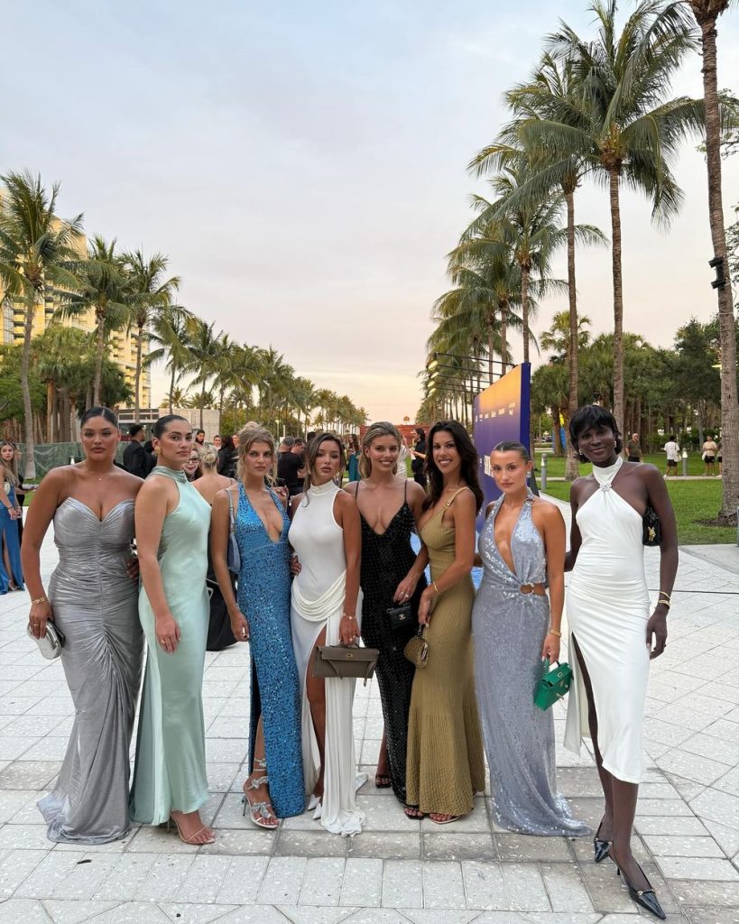 Group of sexy women showing cleavage in pretty dresses among palm trees