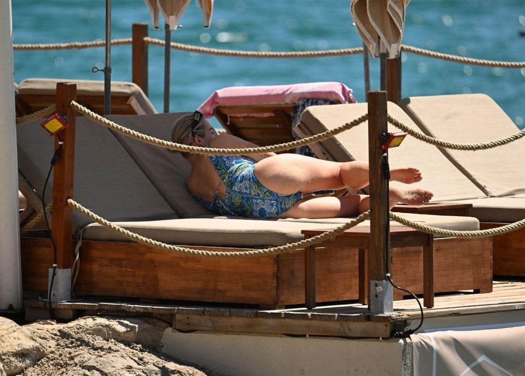 Woman in a swimsuit laying down in a sun chair at the beach