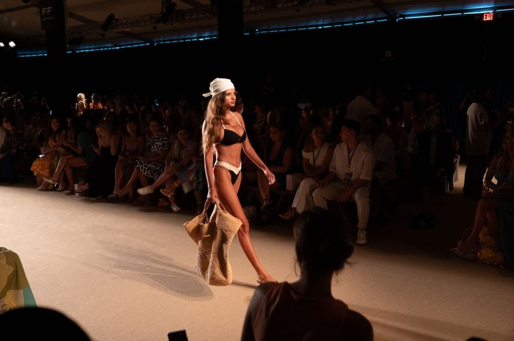 Audience watching a sexy bikini model walking the runway at a fashion show