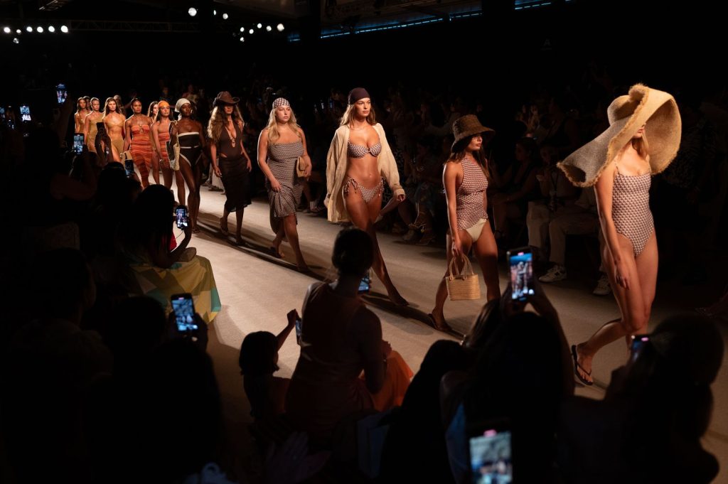 A long line of models walking the runway in swimwear
