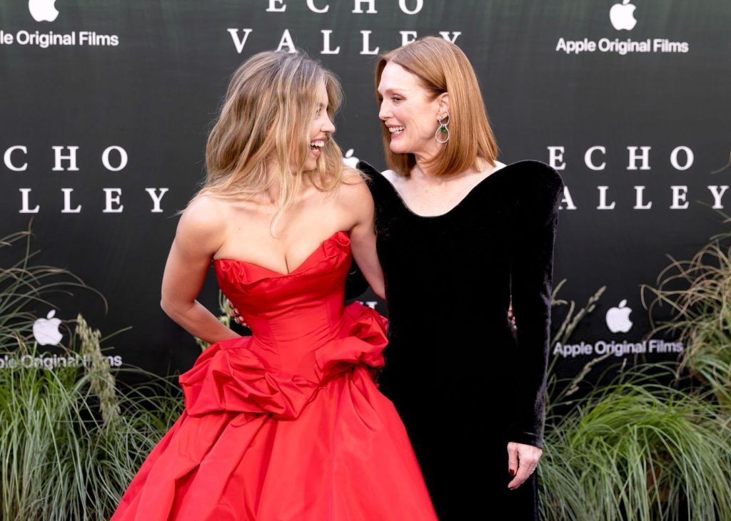 Sydney Sweeney and Julianne Moore looks at each other and share a laugh while posing together at a movie premiere