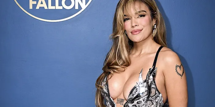 Busty Colombian popstar in a sexy dress posing in front of a blue wall