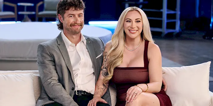 Sexy blonde wife sitting on a porn couch next to her husband