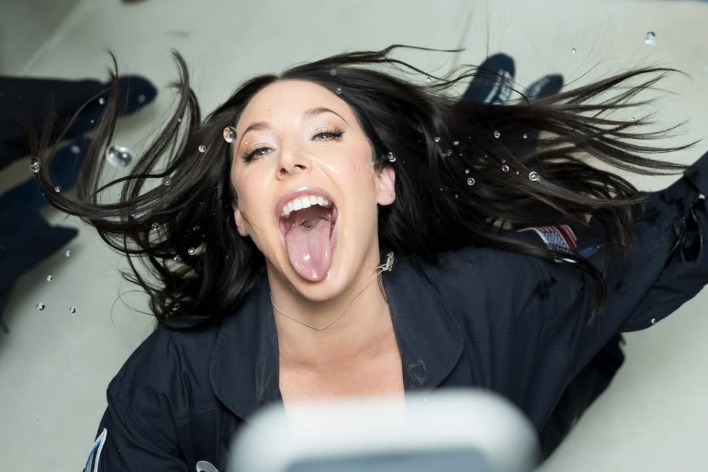 Angela White with her tongue out and floating in zero gravity