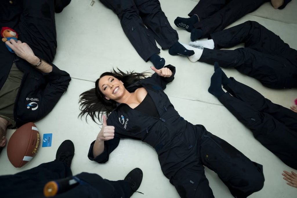 Angela White on the floor in a space suit