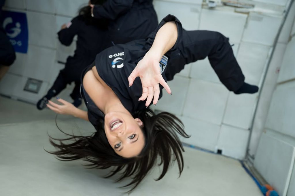 Angela White floating uopside down in zero gravity