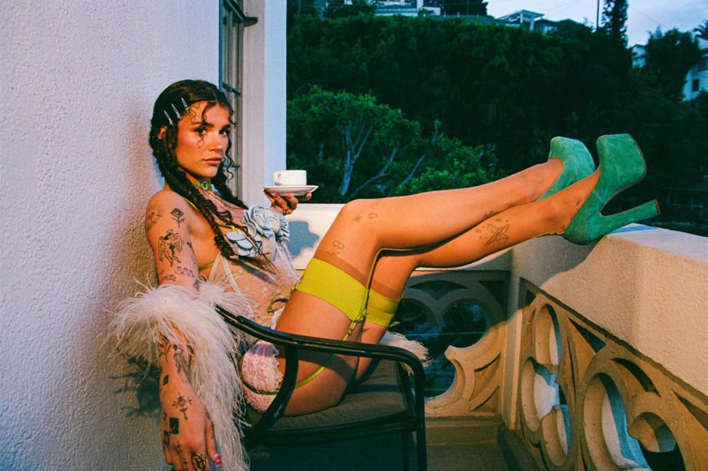 Sexy brunette in pigtails wearing lingerie while enjoying a cup of coffee on a balcony