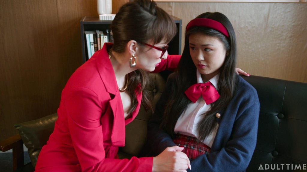 Strict lady leans in towards a shy Asian girl to give her a talking to
