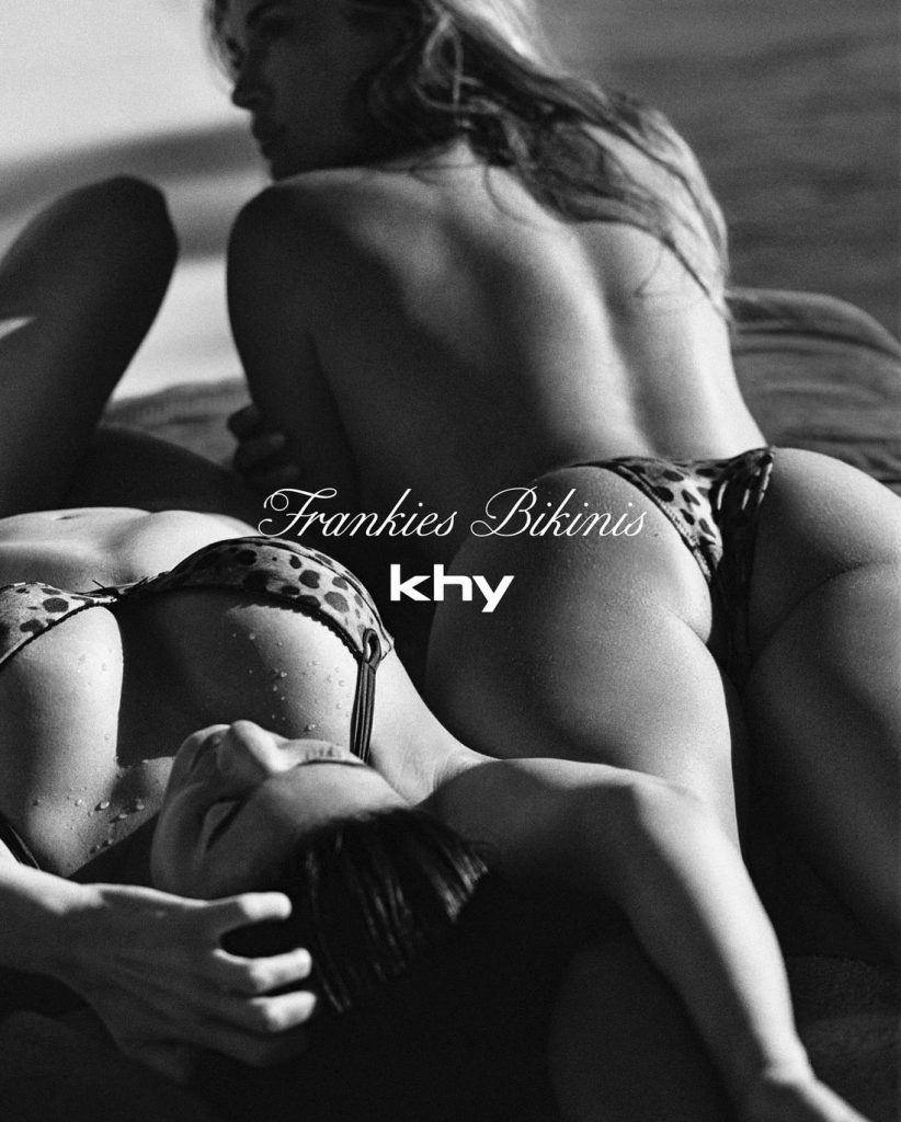 Black and white photo of two sexy bikini girls laying down. One on her stomach and one on her back