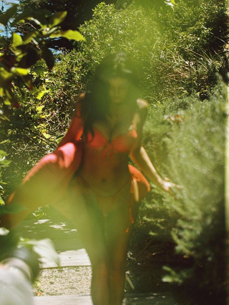 Kylie Jenner walking in a red bikini being obscured by plants