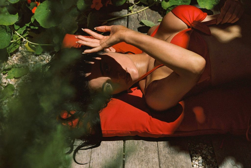 Kylie Jenner shield her eyes from the sun while laying on her back in a red bikini