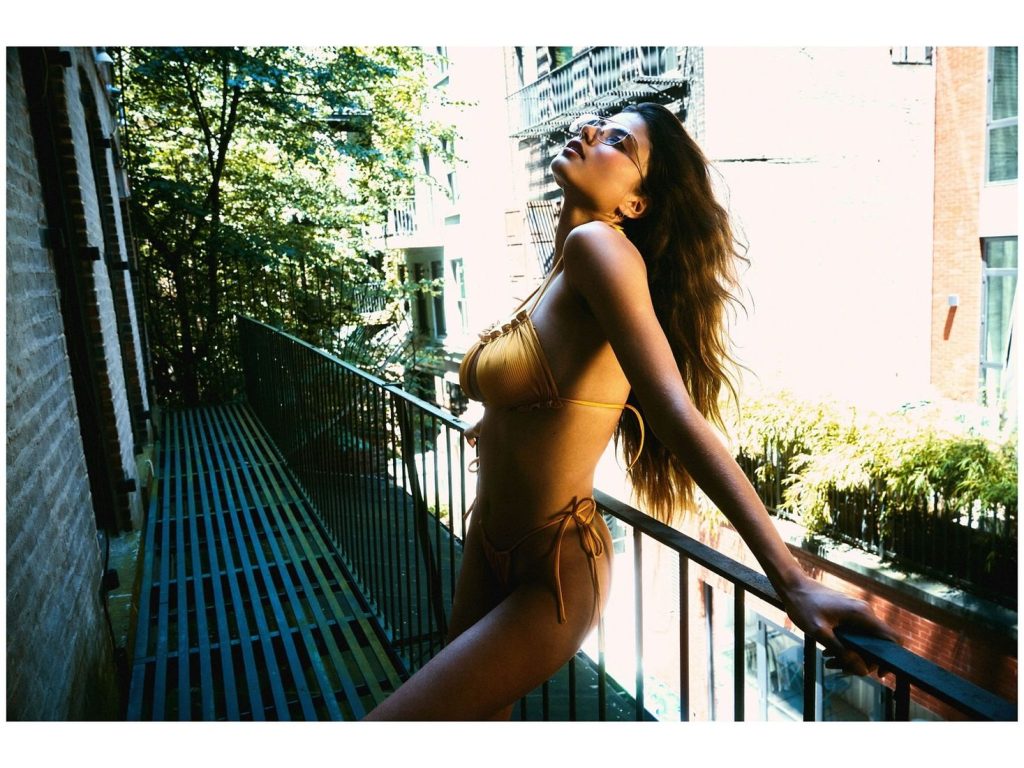 Sexy bikini babe leaning back on a balcony railing