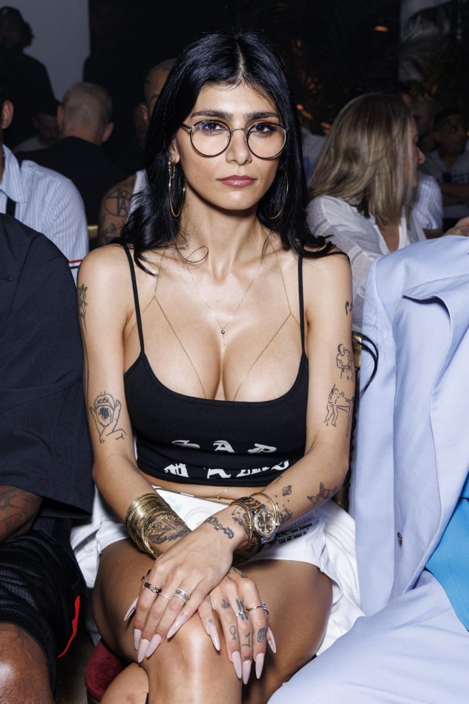 Close up of brunette showing big tit cleavage in a black top while sitting in the audience of a fashion show