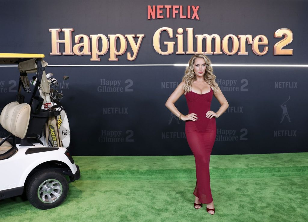 Busty blonde in a red dress posing on the grass at Happy Gilmore 2 premiere