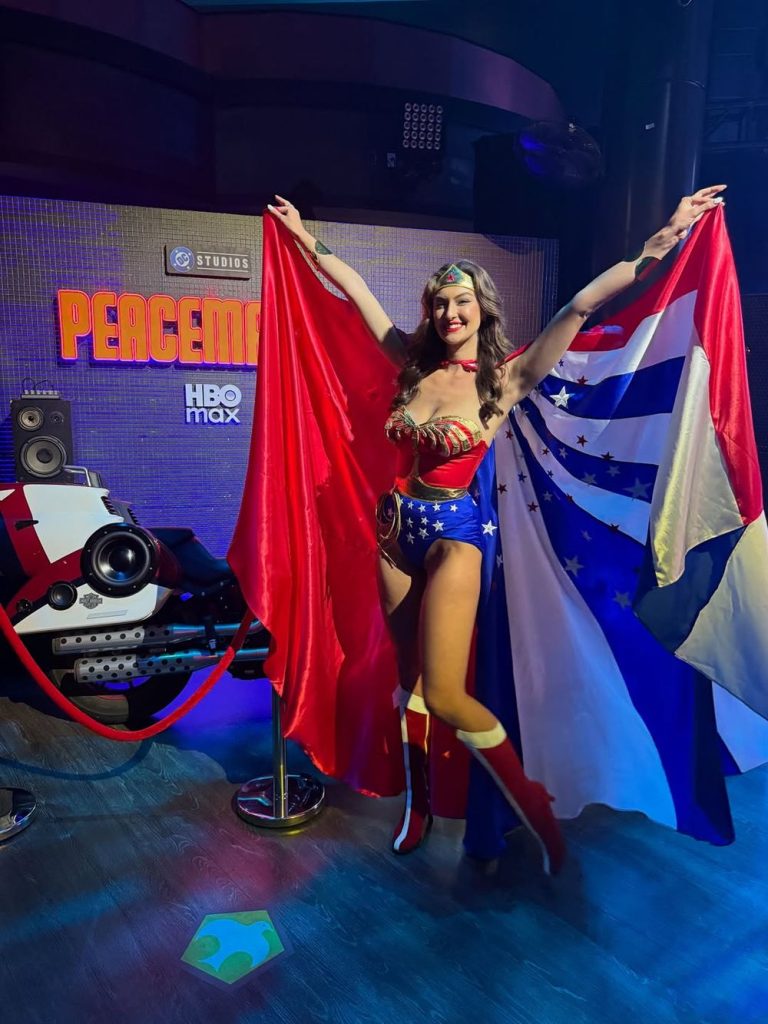 Rachel Pizzolato lift her arms up in the air while she is wearing a Wonder Woman costume