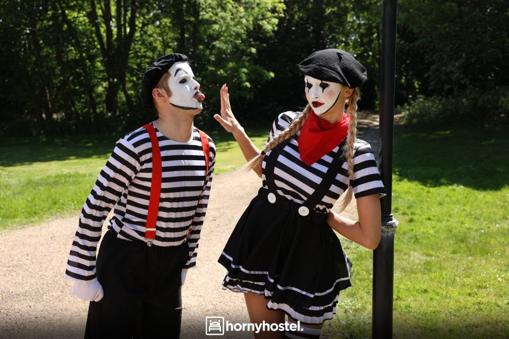 Blonde mime giving a male mime the hand while he tries to give her a kiss