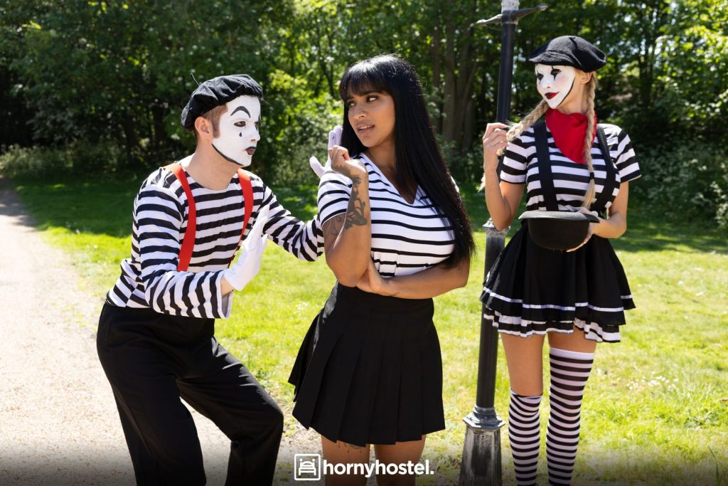 Sexy brunette standing between a male and female mime in the park