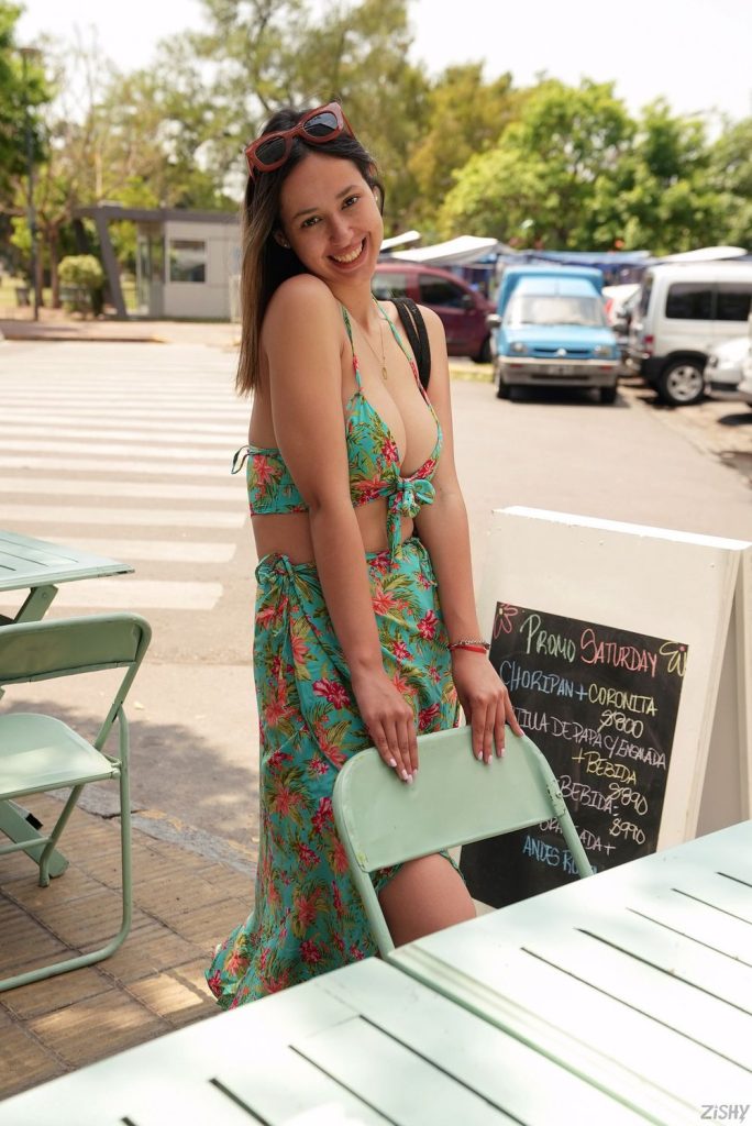 Pretty Latina braless in a sun dress and squeezing her big boobs together outside a restaurant