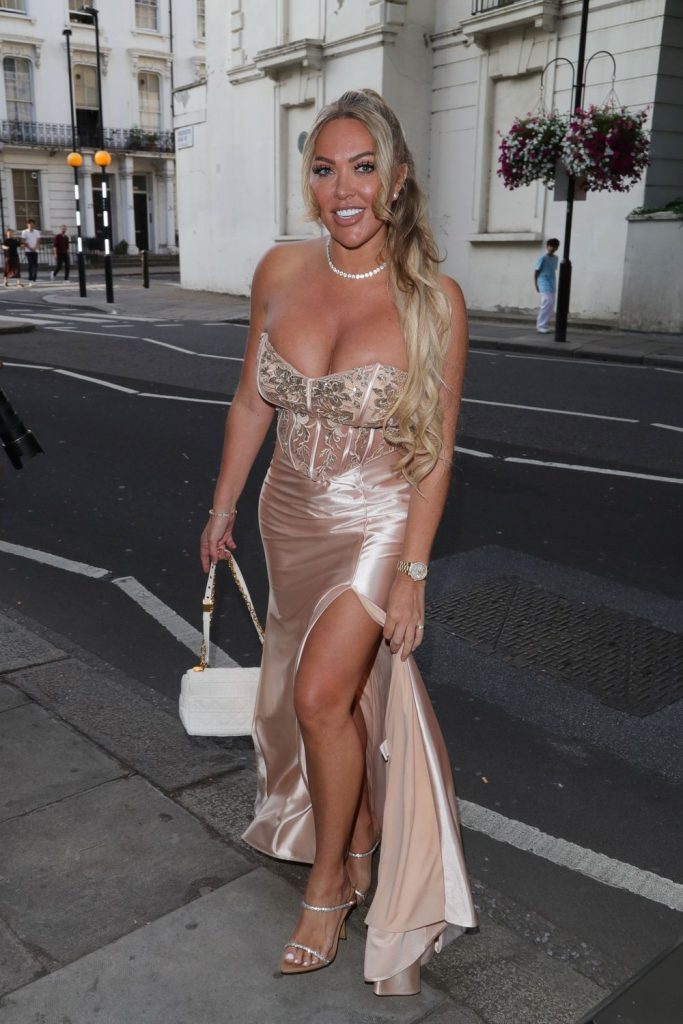 Big boob blonde looks into the camera as she is crossing a street in a beautiful dress