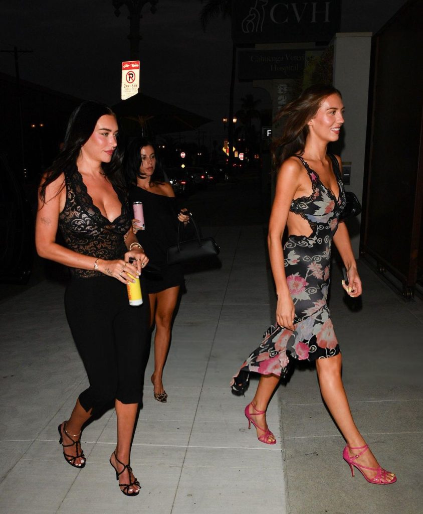 Two women seen from the side as they are crossing a street in sexy dresses at night