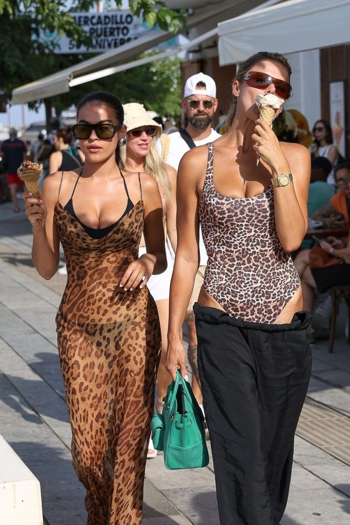 Two sexy sisters showing cleavage while eating ice cream on a public sidewalk