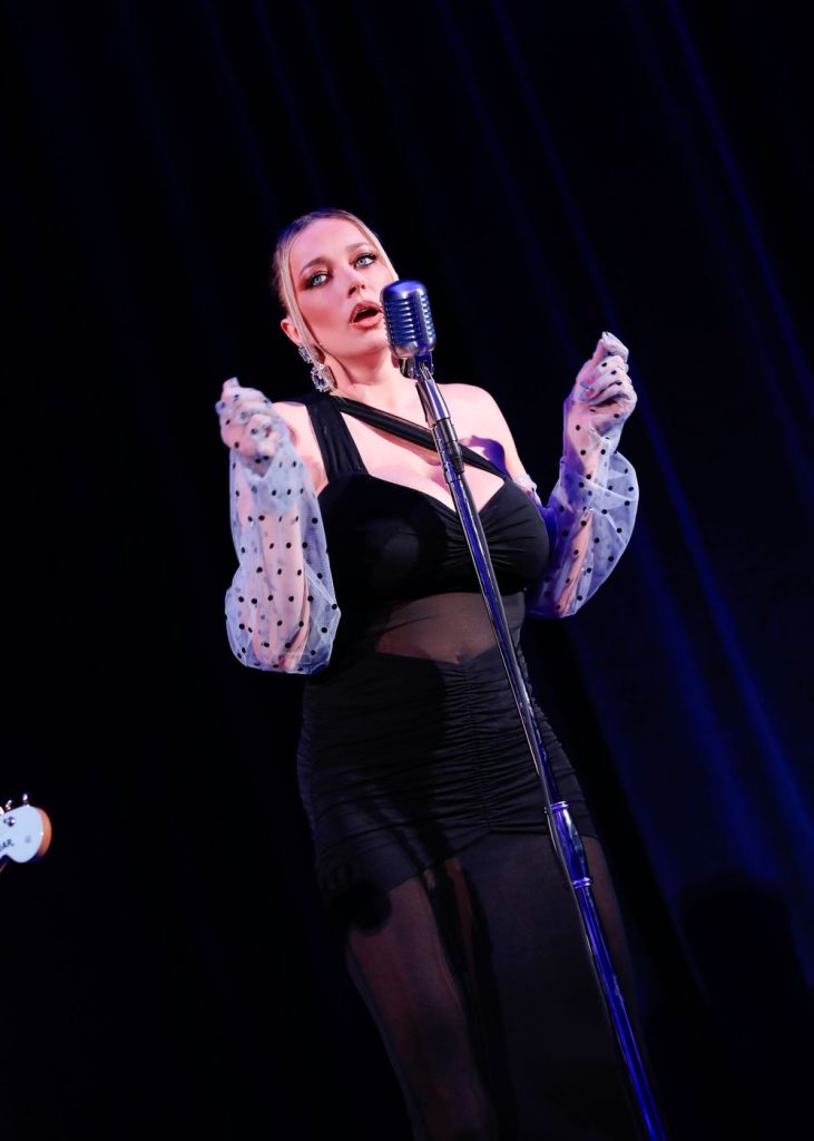 Beautiful blonde singer performs on stage with moody blue lighting