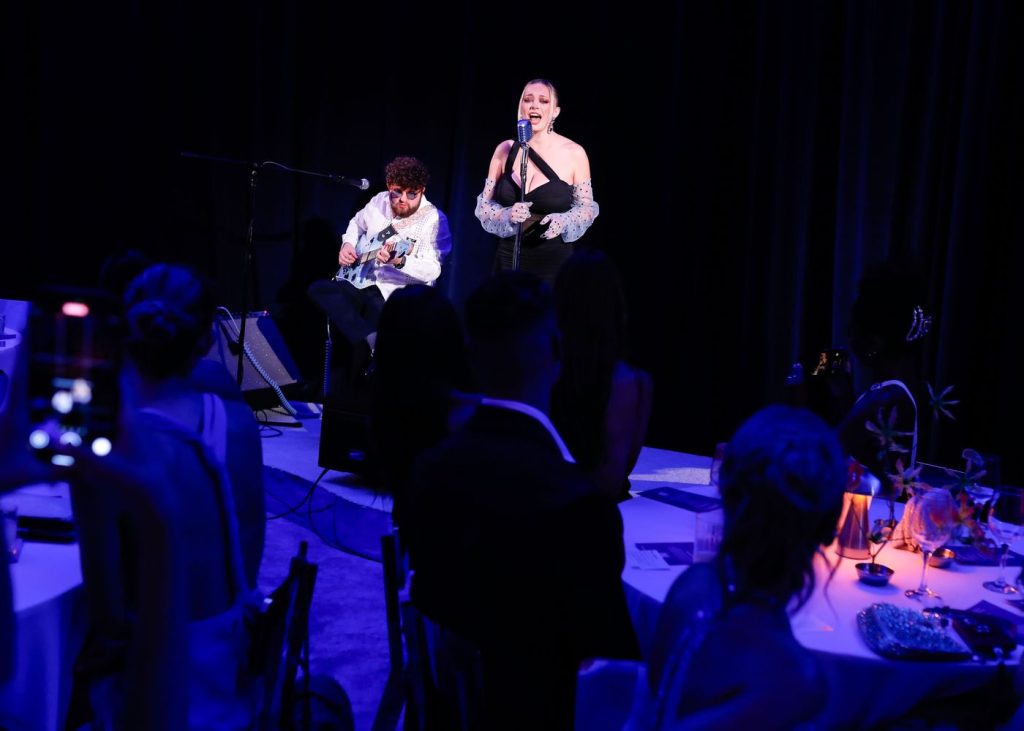 Beautiful blonde singer performs on stage with moody blue lighting