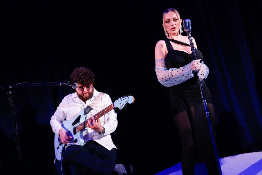 Beautiful blonde singer performs on stage with moody blue lighting