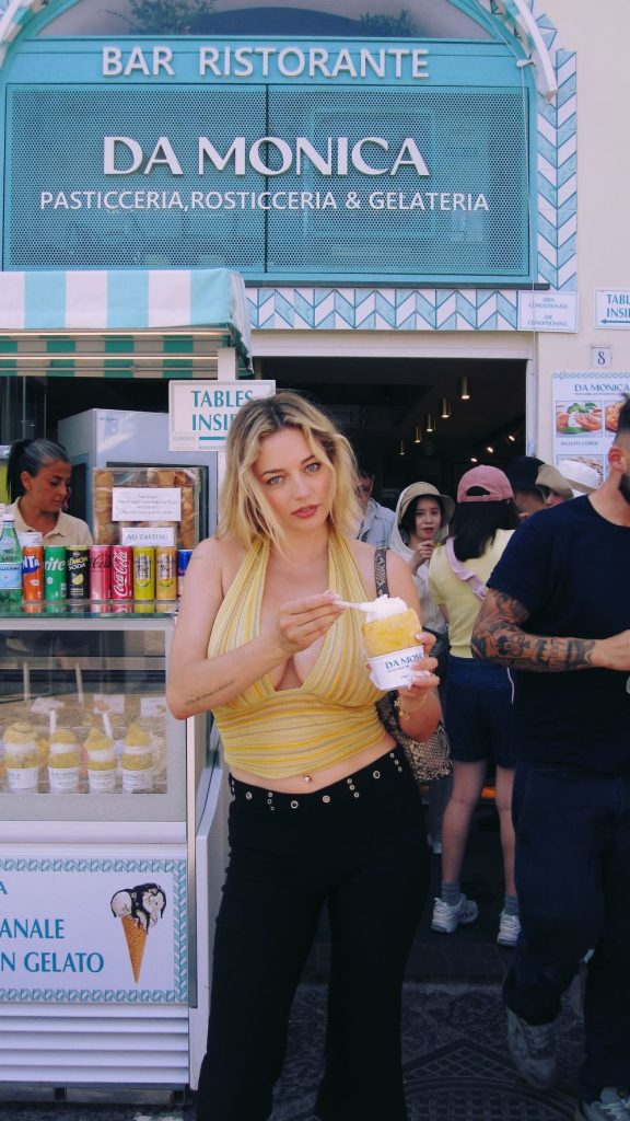 Busty blonde in a sexy top posing in front of an ice cream shop