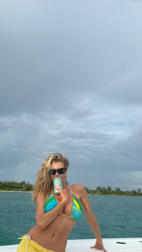 Busty blonde having a drink from a can while in a bikini on a boat