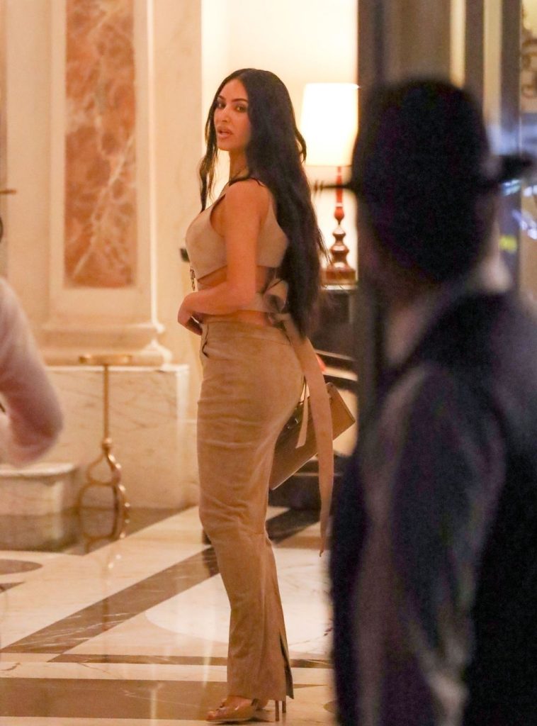 Kim Kardashian curvy from the side in a tight dress while inside a fancy building in Italy