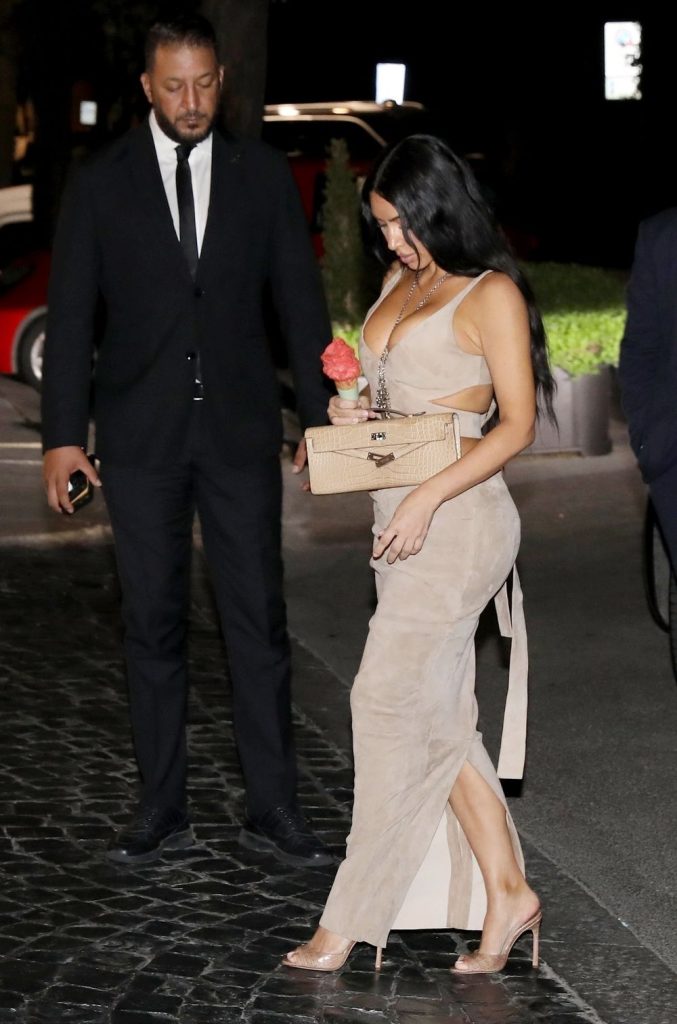 Kim Kardashian walking in a tight dress and looking down at the ice cream she is holding