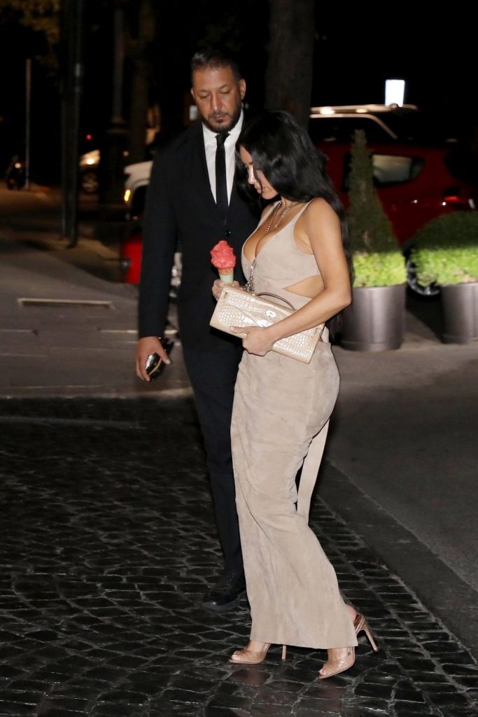 Kim Kardashian seen from the side and walking in a tight and sexy dress while holding ice cream