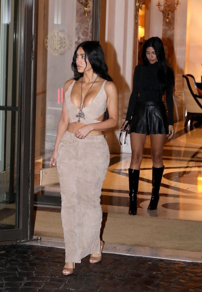 Kim Kardashian look to the side while leaving a building in a tight dress
