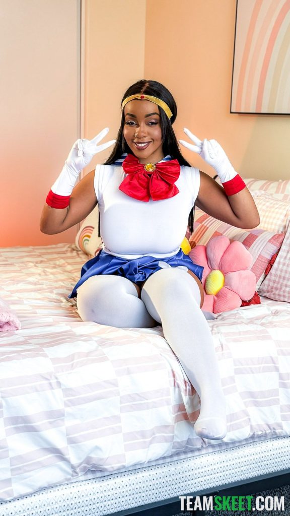 Ebony babe sitting on bed while dressed as Sailor Moon