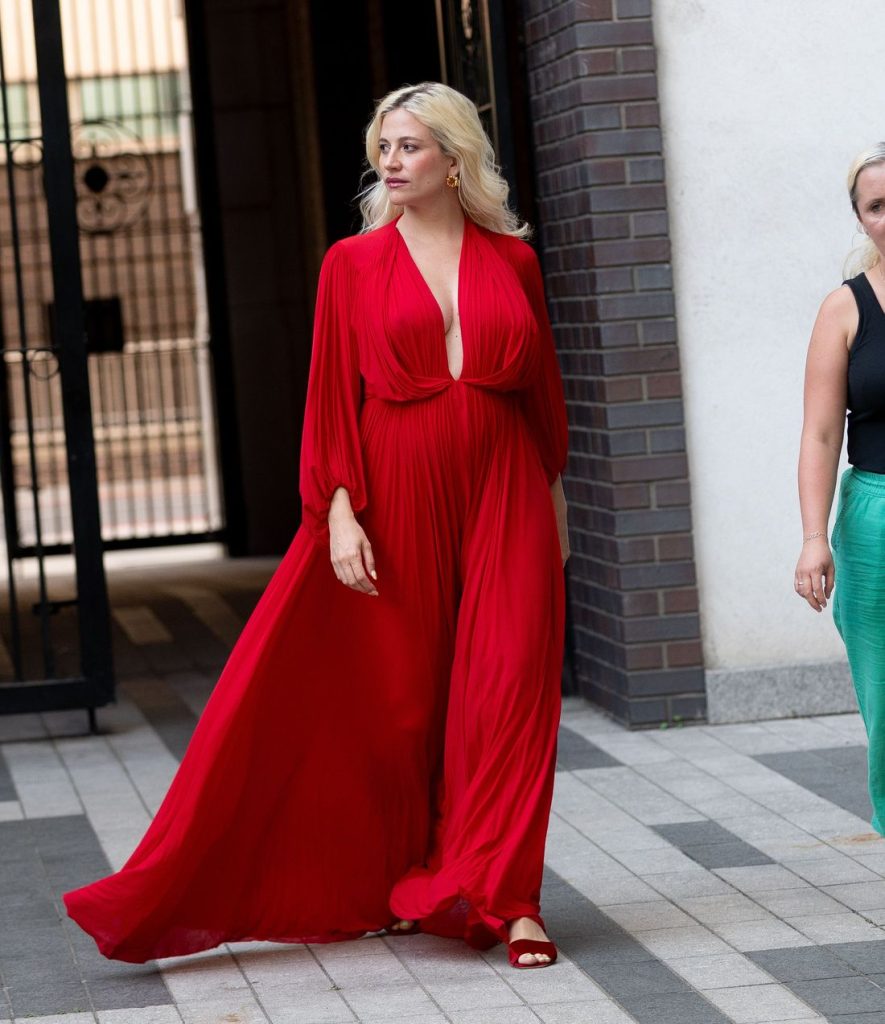 Blonde woman looks off to the side while showing very nice cleavage while on the move in a beautiful red dress