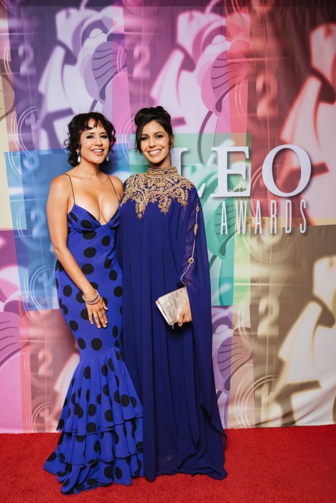 Agam Darshi and another woman posing on the red carpet in blue dresses