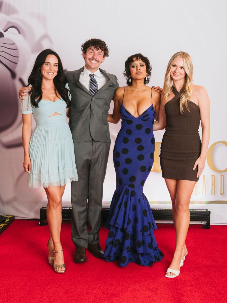 Agam Darshi showing cleavage while posing with a group of people on the red carpet