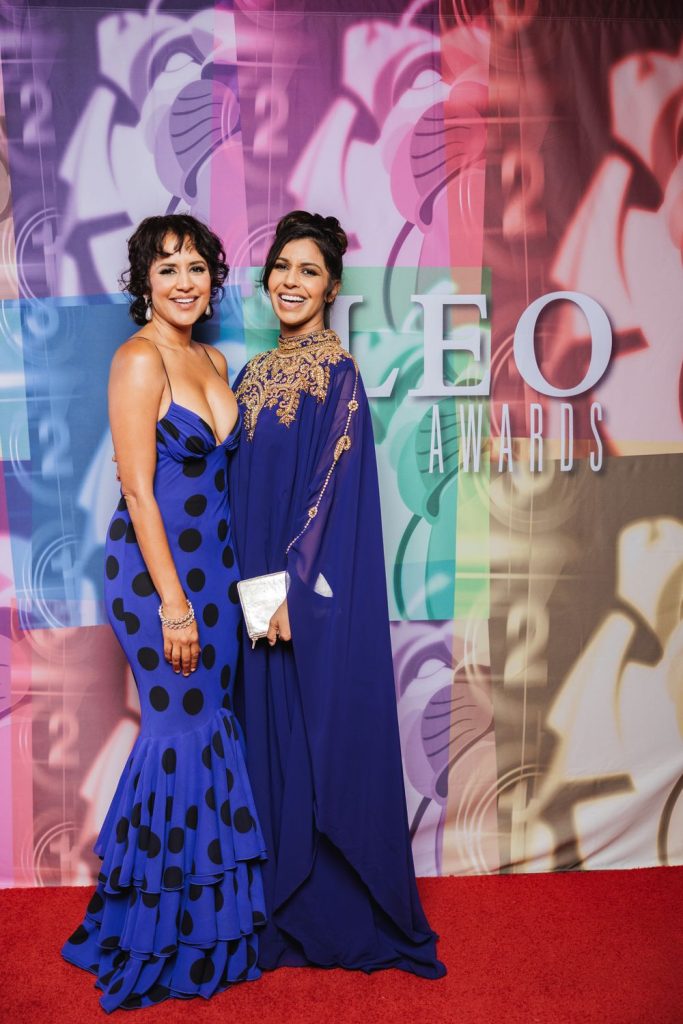 Agam Darshi and another woman posing on the red carpet in blue dresses