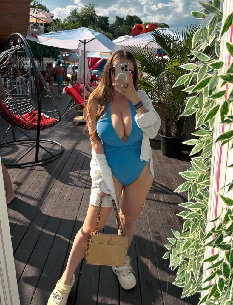 Big boob babe snaps a selfie in a blue swimsuit