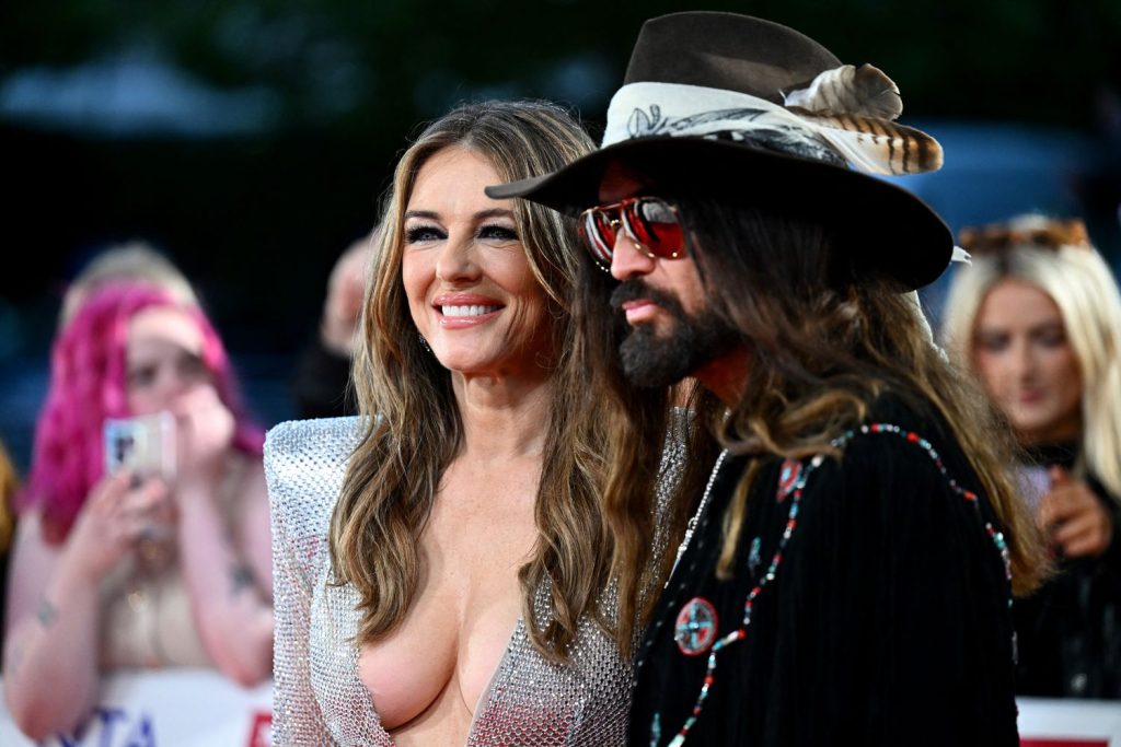 Elizabeth Hurley looking straight forward close up while posing next to a man in black