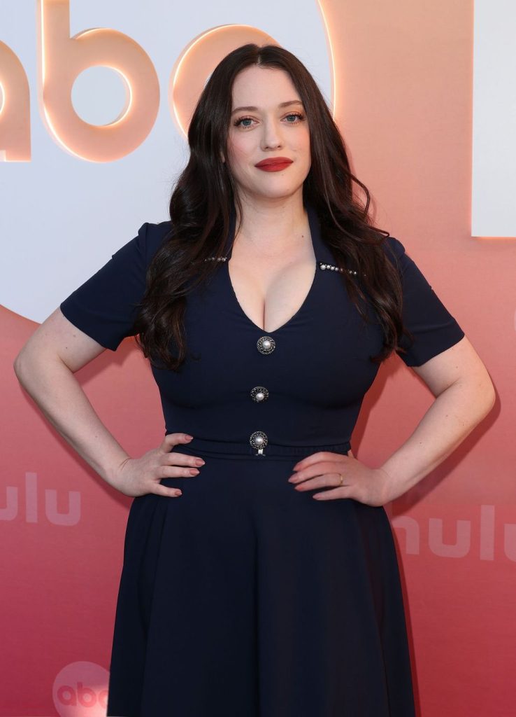 Close up of Kat Dennings in a blue dress and hands on hips